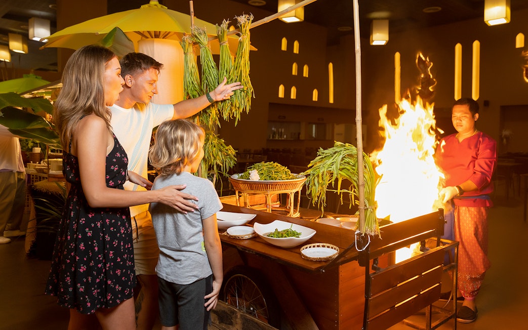 Family enjoying buffet dinner at Siam Niramit with live cooking station.