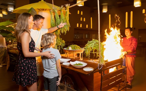 Family enjoying buffet dinner at Siam Niramit with live cooking station.