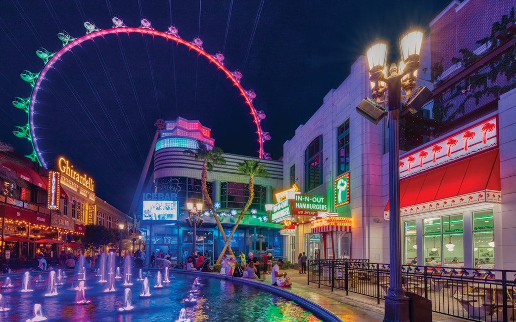 The LINQ Promenade at night with High Roller observation wheel and fountain.