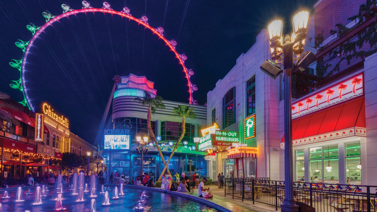 The LINQ Promenade at night with High Roller observation wheel and fountain.