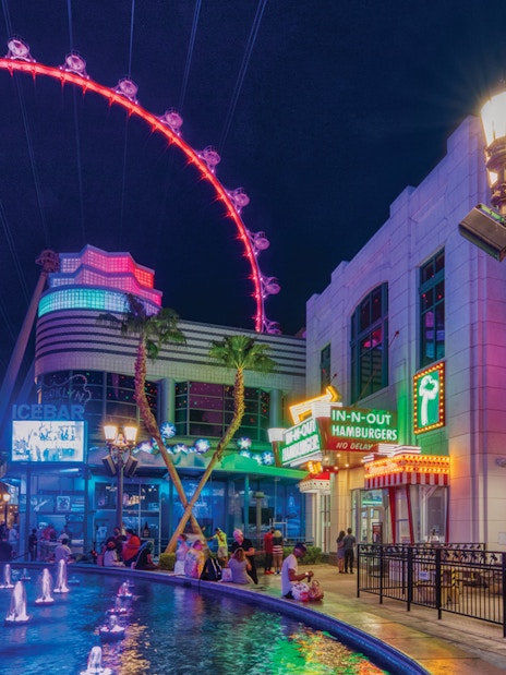 The LINQ Promenade at night with High Roller observation wheel and fountain.