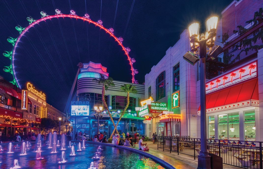 The LINQ Promenade at night with High Roller observation wheel and fountain.