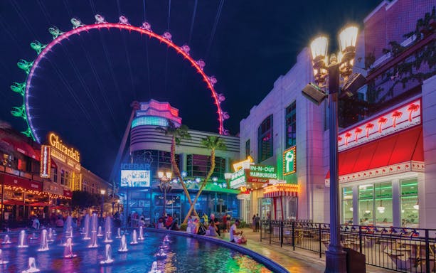 The LINQ Promenade at night with High Roller observation wheel and fountain.