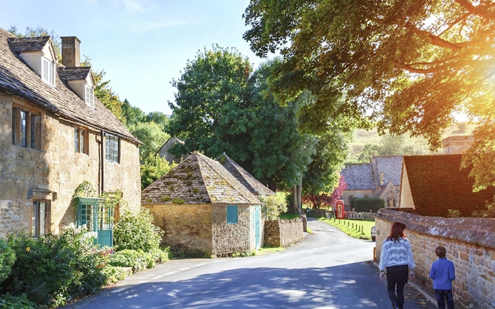 Cotswolds village street with stone cottages and lush greenery, part of small group tour.