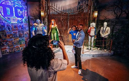 Tourist photographing family near DC exhibit at Warner Bros. Studio.