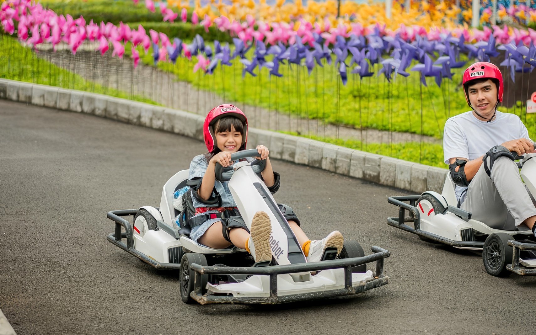Go-karting at Dairyland Farm Theme Park Puncak with colorful pinwheels in the background.