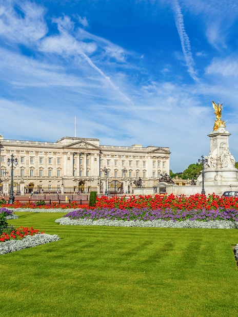 Buckingham Palace with Victoria Memorial and vibrant flower gardens in London.