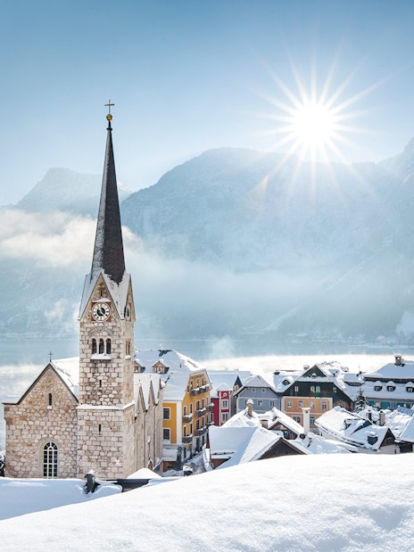 Church and snow-covered village in Hallstatt, Austria, with mountains in winter.