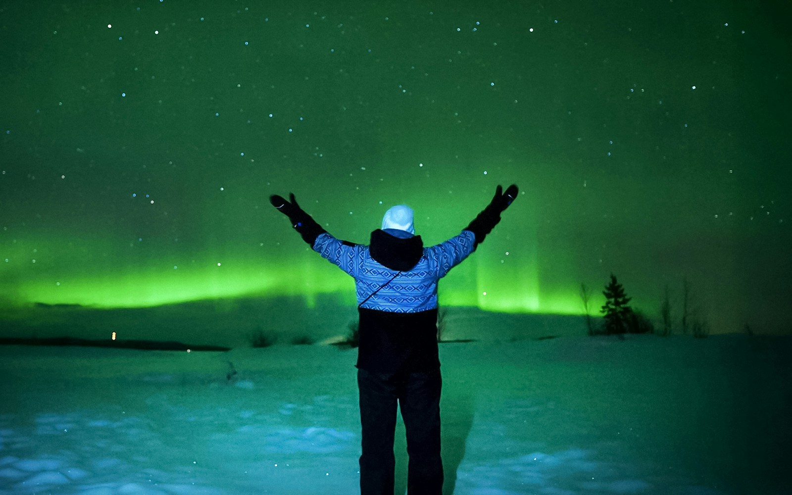 Person viewing Northern Lights in Tromso, Norway, with arms raised.