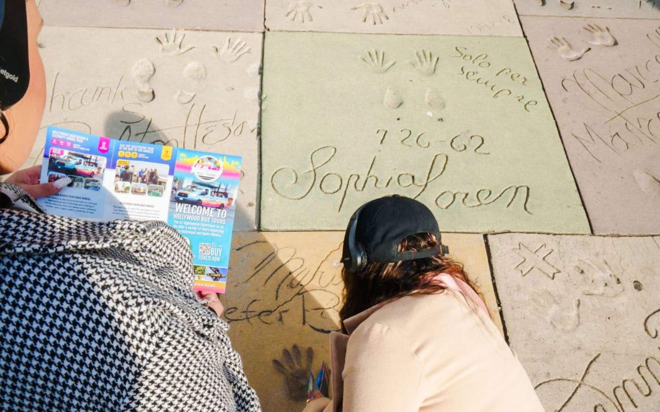 Guests examining celebrity handprints on Hollywood Walk of Fame tour.