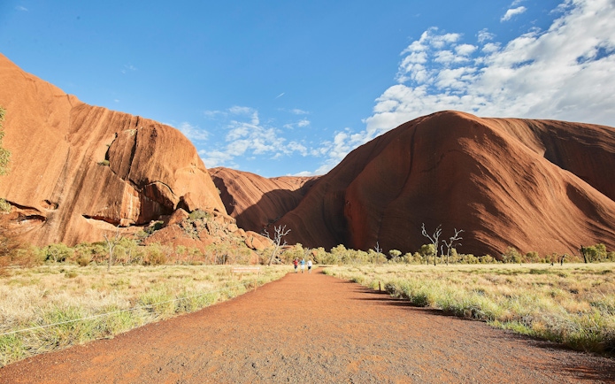 Uluru at sunrise with tourists walking on a guided tour, Australia.