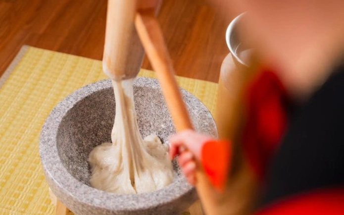 Mochi being pounded in a stone mortar during a traditional Kyoto experience.