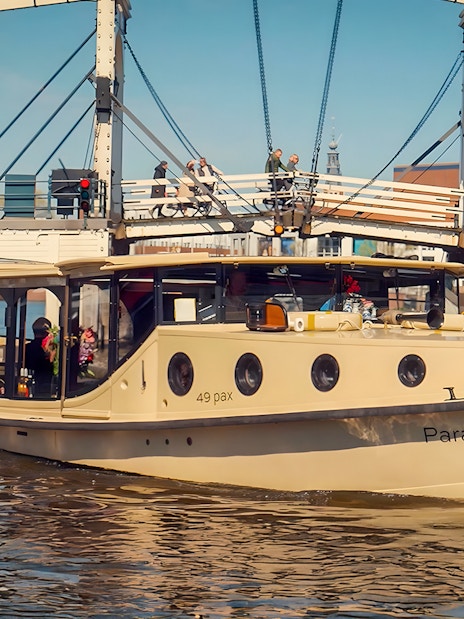 Historic luxury boat on Amsterdam canal near a drawbridge, part of 17th Century VR Cruise.