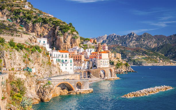 Colorful cliffside village along the Amalfi Coast, Italy, with arched bridges and blue sea.