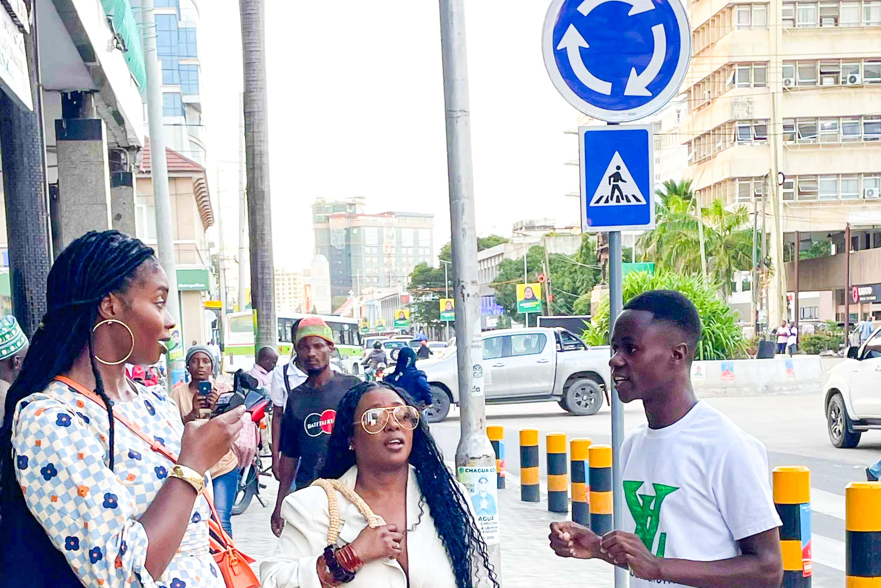 Tour guide speaking with tourists on a street in Zanzibar, with cityscape in the background.