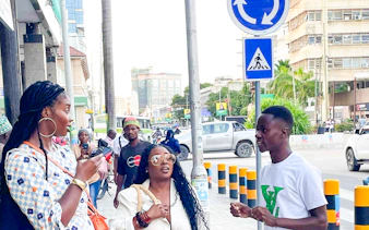 Tour guide speaking with tourists on a street in Zanzibar, with cityscape in the background.
