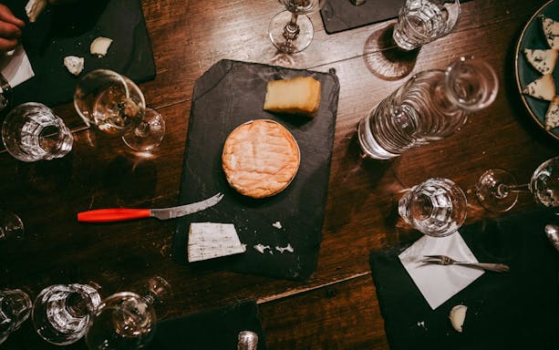 Cheese tasting setup at Paroles de Fromagers in Paris, France with various cheeses and wine glasses.