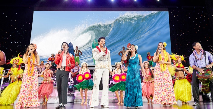 Performers on stage at Rock-A-Hula Show in Honolulu, Hawaii, showcasing vibrant Hawaiian dance and music.
