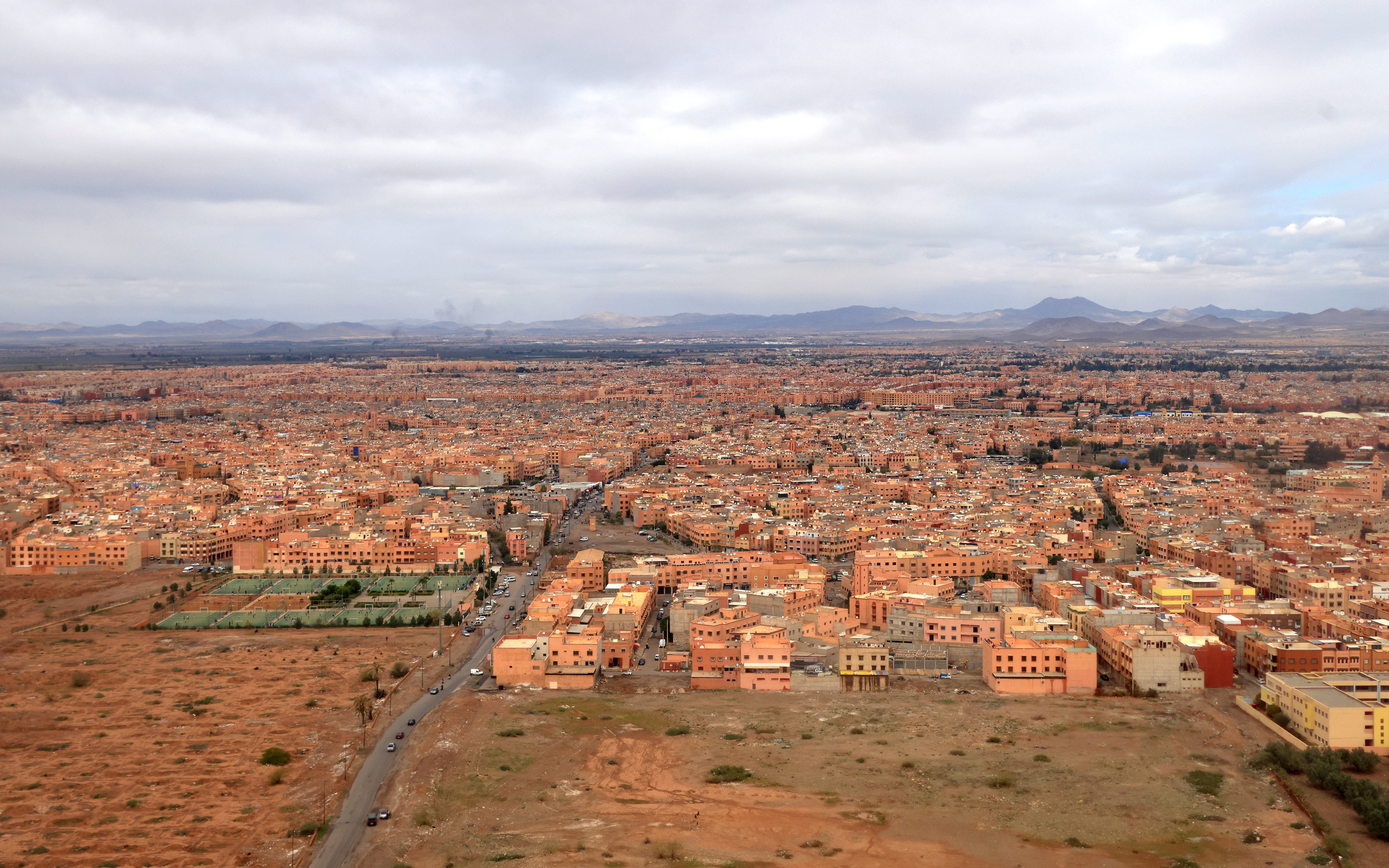Aerial view of Marrakech, Morocco, showcasing sprawling cityscape and distant Atlas Mountains.