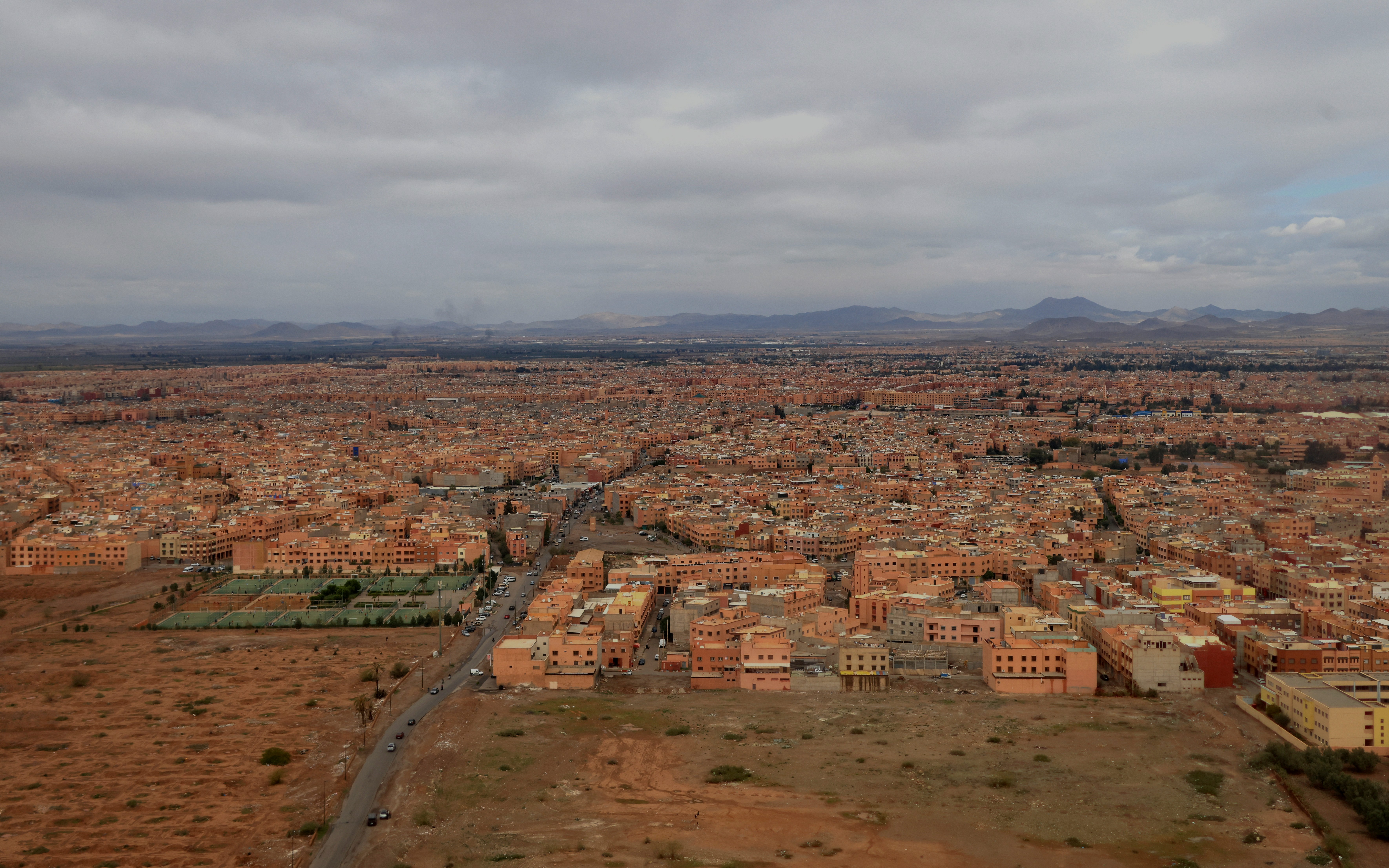 Aerial view of Marrakech, Morocco, showcasing sprawling cityscape and distant Atlas Mountains.