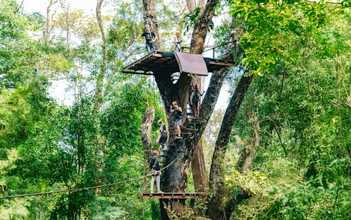 Participants on a zipline platform in a lush forest at Flying Hanuman, Phuket.