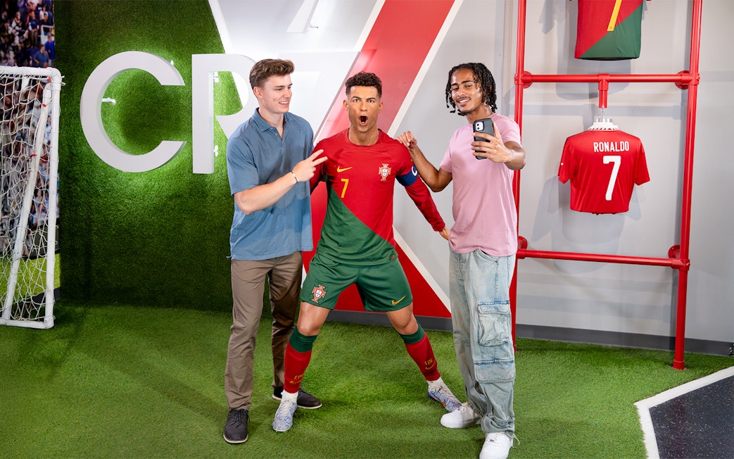 Two men taking a selfie with Ronaldo's wax figure at Madame Tussauds, New York.