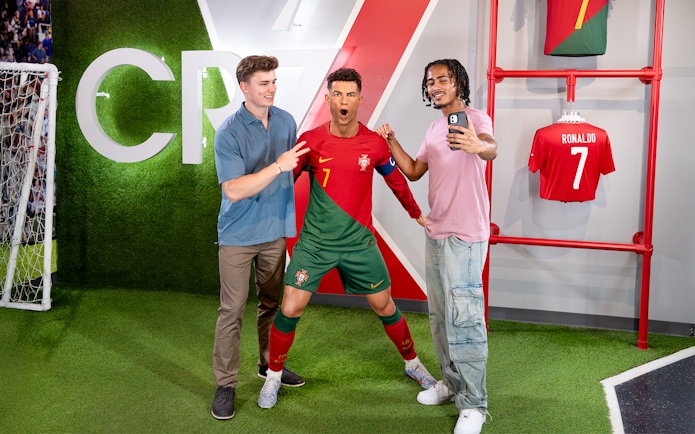 Two men taking a selfie with Ronaldo's wax figure at Madame Tussauds, New York.