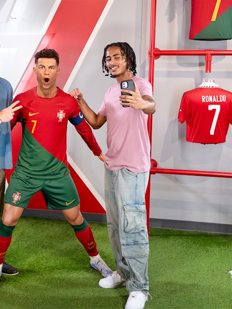 Two men taking a selfie with Ronaldo's wax figure at Madame Tussauds, New York.