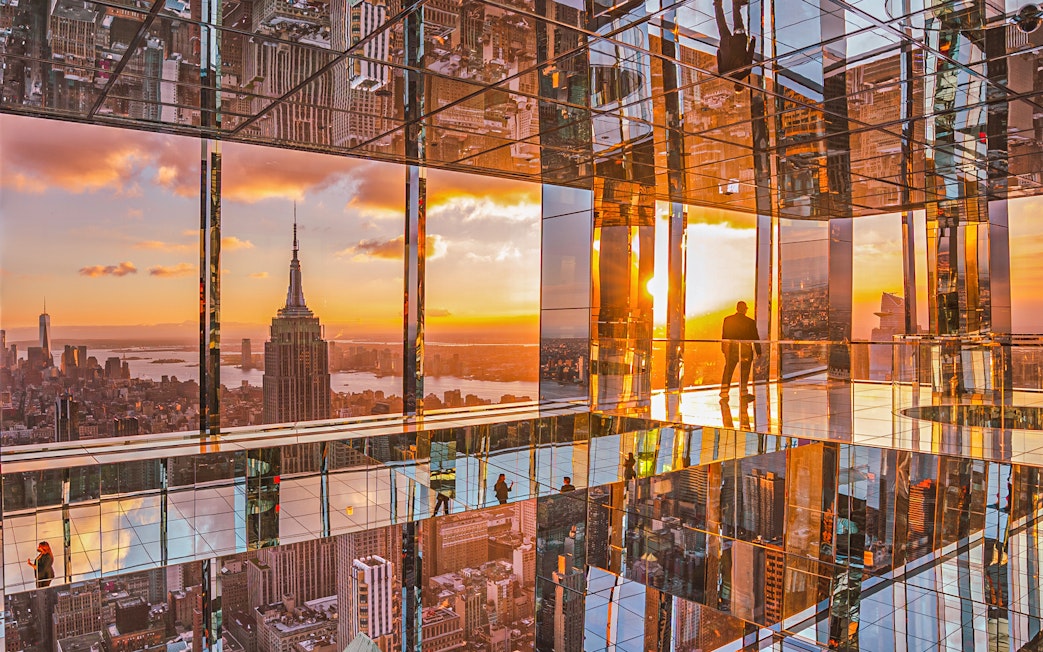 Cityscape sunset view from mirrored observation deck, featuring iconic skyline.