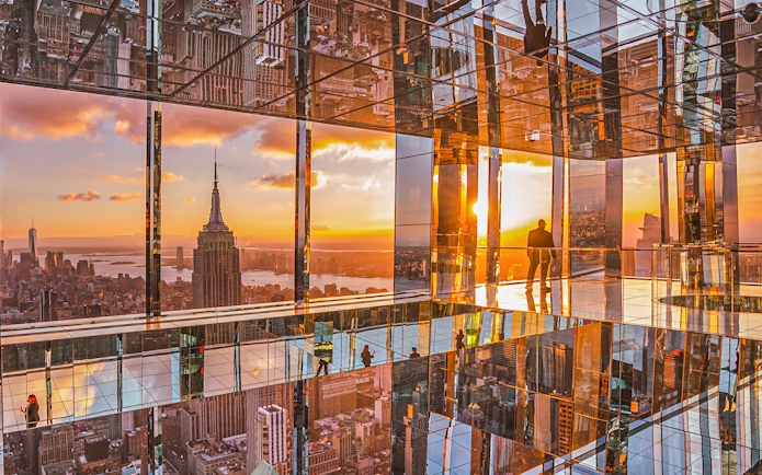 Cityscape sunset view from mirrored observation deck, featuring iconic skyline.