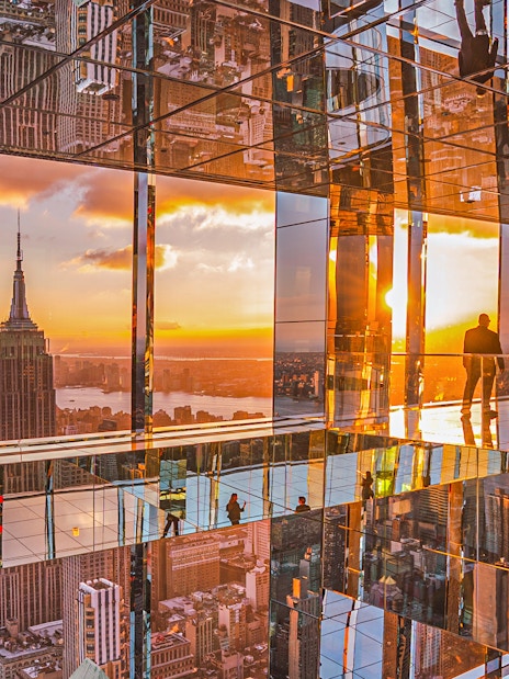 Cityscape sunset view from mirrored observation deck, featuring iconic skyline.