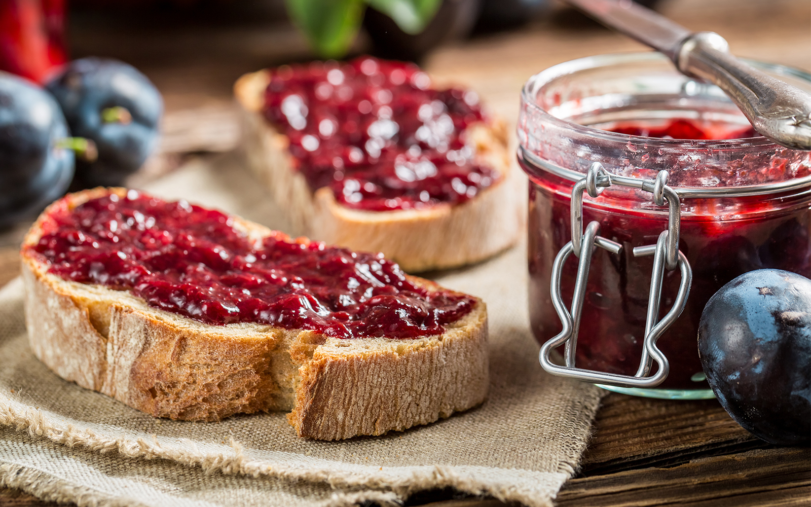Jam spread on bread kept beside a jar of jam