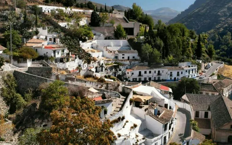 Granada Sacromonte hillside with whitewashed houses and narrow streets, part of self-guided city exploration game.