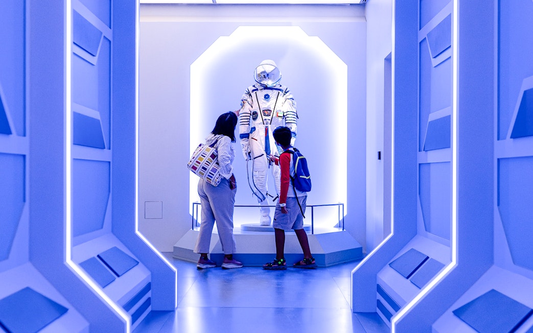 Visitors observing a space exhibit at Louvre Abu Dhabi.