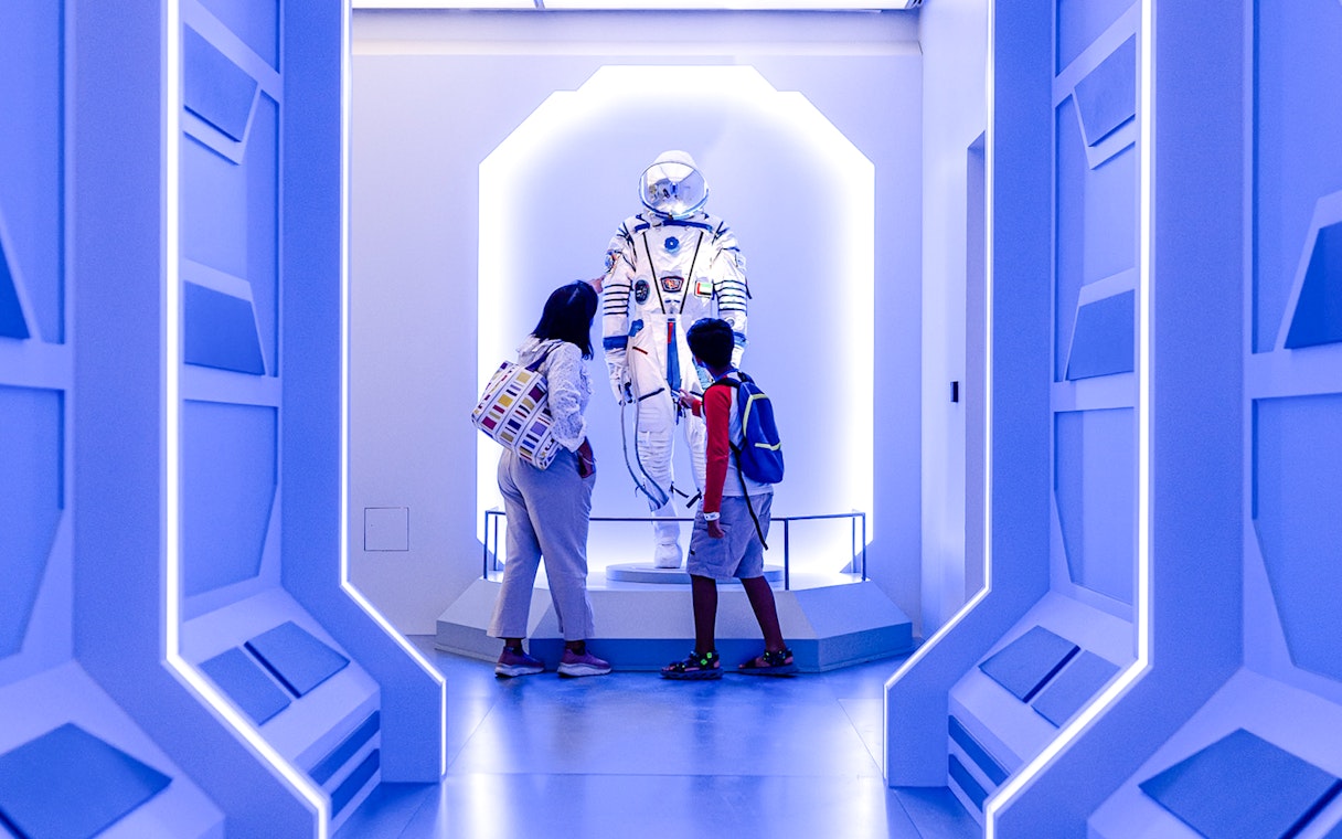 Visitors observing a space exhibit at Louvre Abu Dhabi.