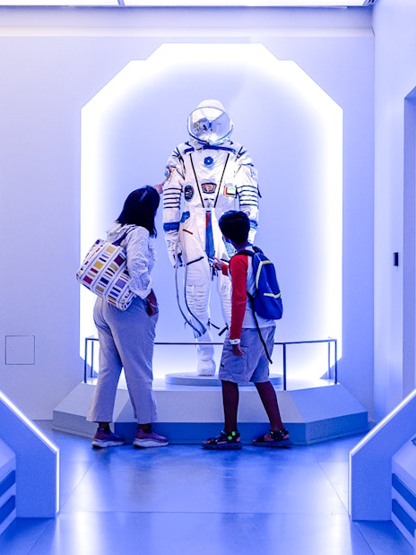 Visitors observing a space exhibit at Louvre Abu Dhabi.