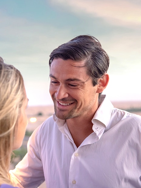 Couple enjoying hot air balloon ride in Dubai desert with balloons in the sky.