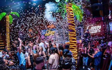 Crowd enjoying a lively night at Coco Bongo Congo Bar with confetti and neon lights.
