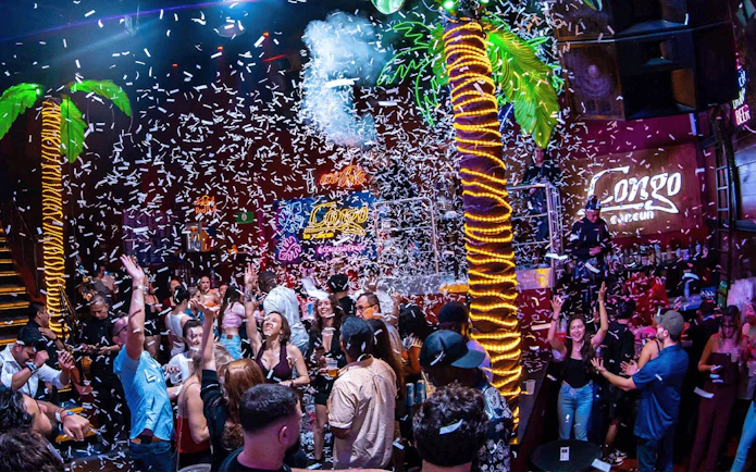 Crowd enjoying a lively night at Coco Bongo Congo Bar with confetti and neon lights.