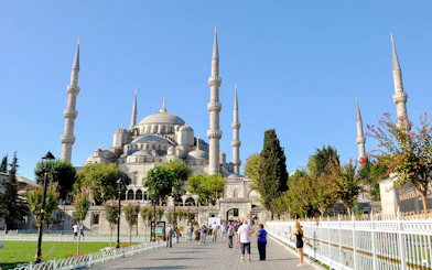 Blue Mosque in Istanbul with tourists walking nearby on a sunny day.
