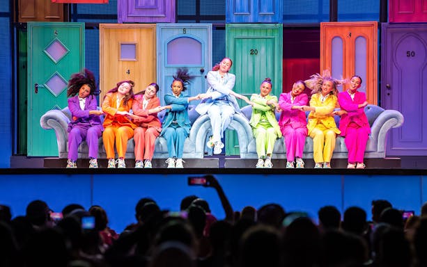 Performers in colorful suits dancing on stage at Global Village Dubai.