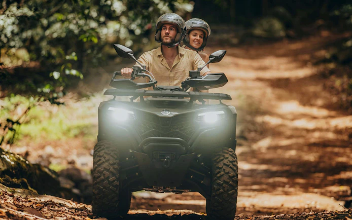 Couple riding a quad bike on a forest trail during Bel Ombre tour.