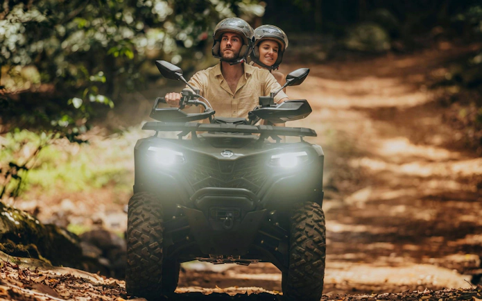 Couple riding a quad bike on a forest trail during Bel Ombre tour.