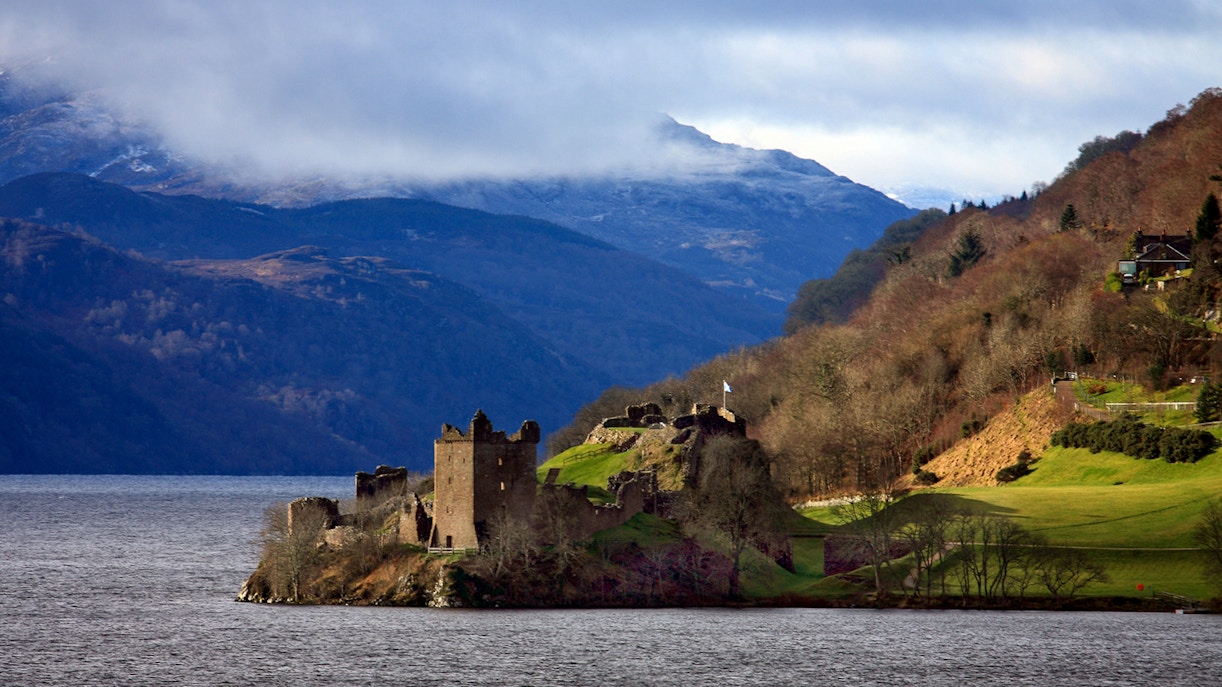 Castle Urquhart overlooking Loch Ness with scenic Highlands backdrop in Inverness, Scotland.