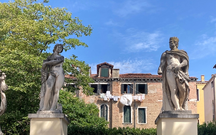 Statues in Ca' Rezzonico Gardens with historic building, Venice.