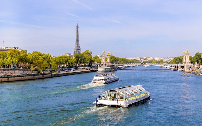 Seine River cruise boats with Eiffel Tower and Pont Alexandre III in Paris.
