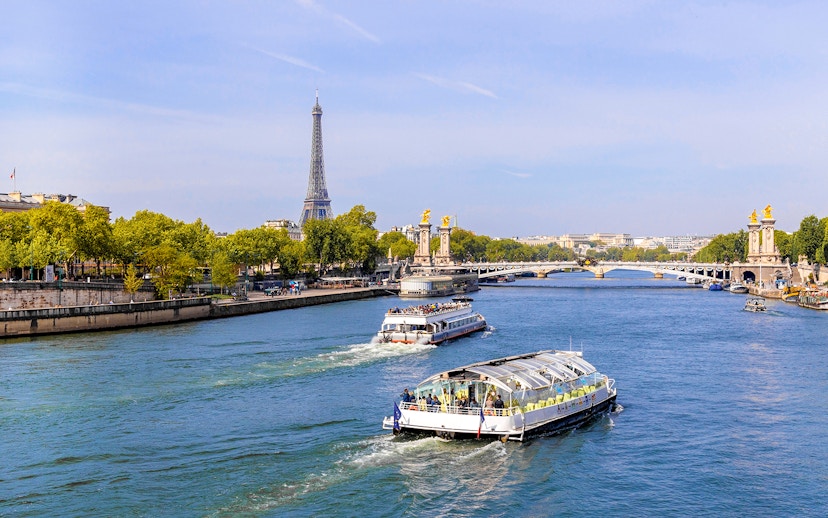 Seine River cruise boats with Eiffel Tower and Pont Alexandre III in Paris.