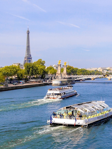 Seine River cruise boats with Eiffel Tower and Pont Alexandre III in Paris.