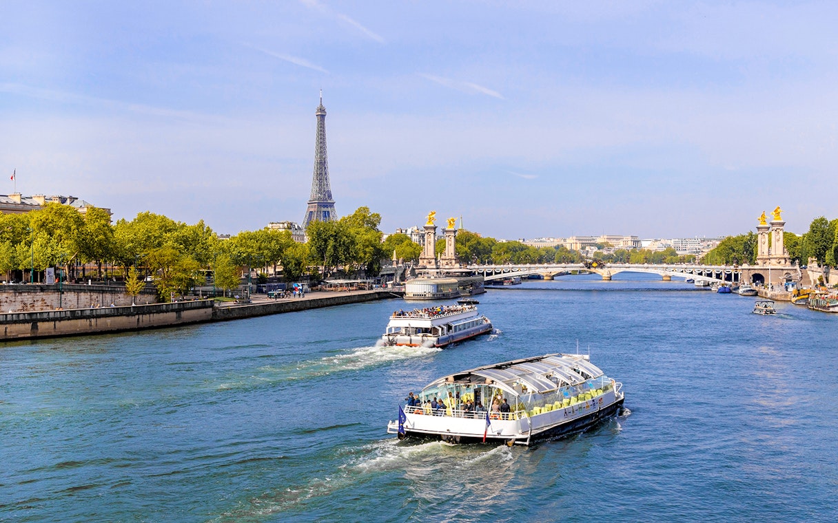 Seine River cruise boats with Eiffel Tower and Pont Alexandre III in Paris.