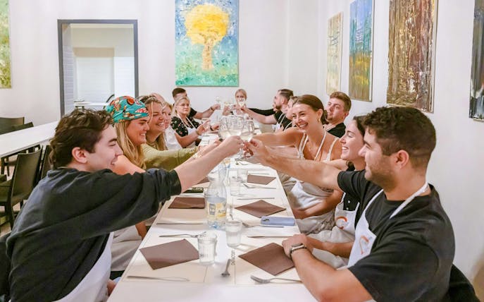 Group enjoying a meal at a Florence cooking class, toasting with wine glasses.